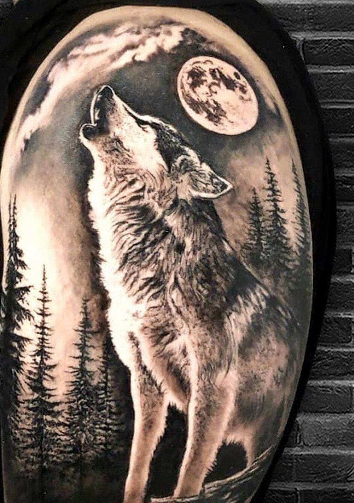 Wolf howling at the moon tattoo with pine trees on a shoulder
