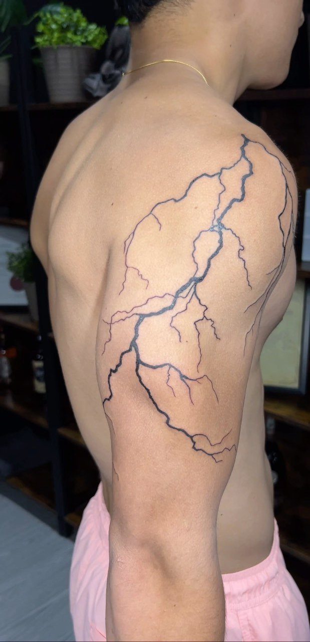 Lightning bolt tattoo on a person's shoulder and upper arm in black ink.