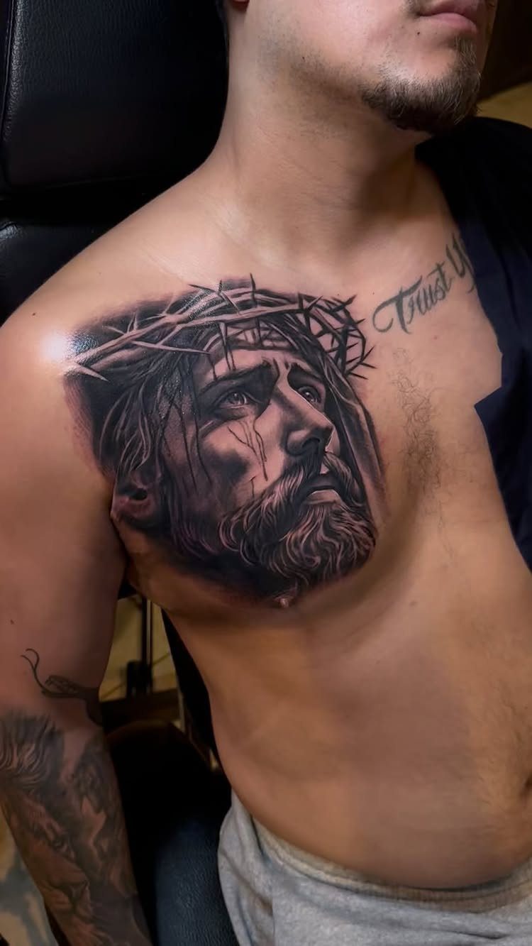 Realistic black and grey portrait tattoo of Jesus with crown of thorns on chest