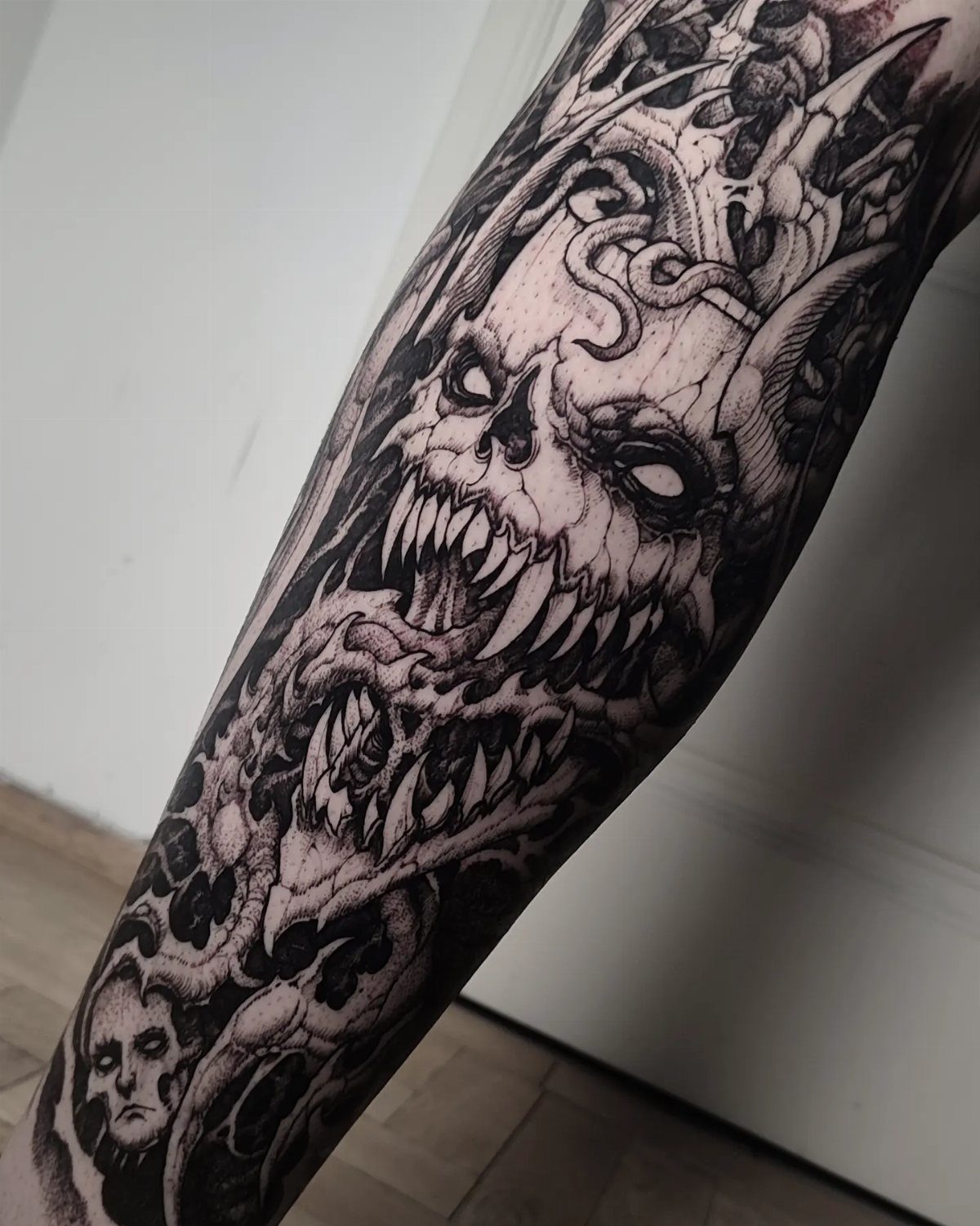 Detailed blackwork tattoo of a demonic skull on a person's arm.