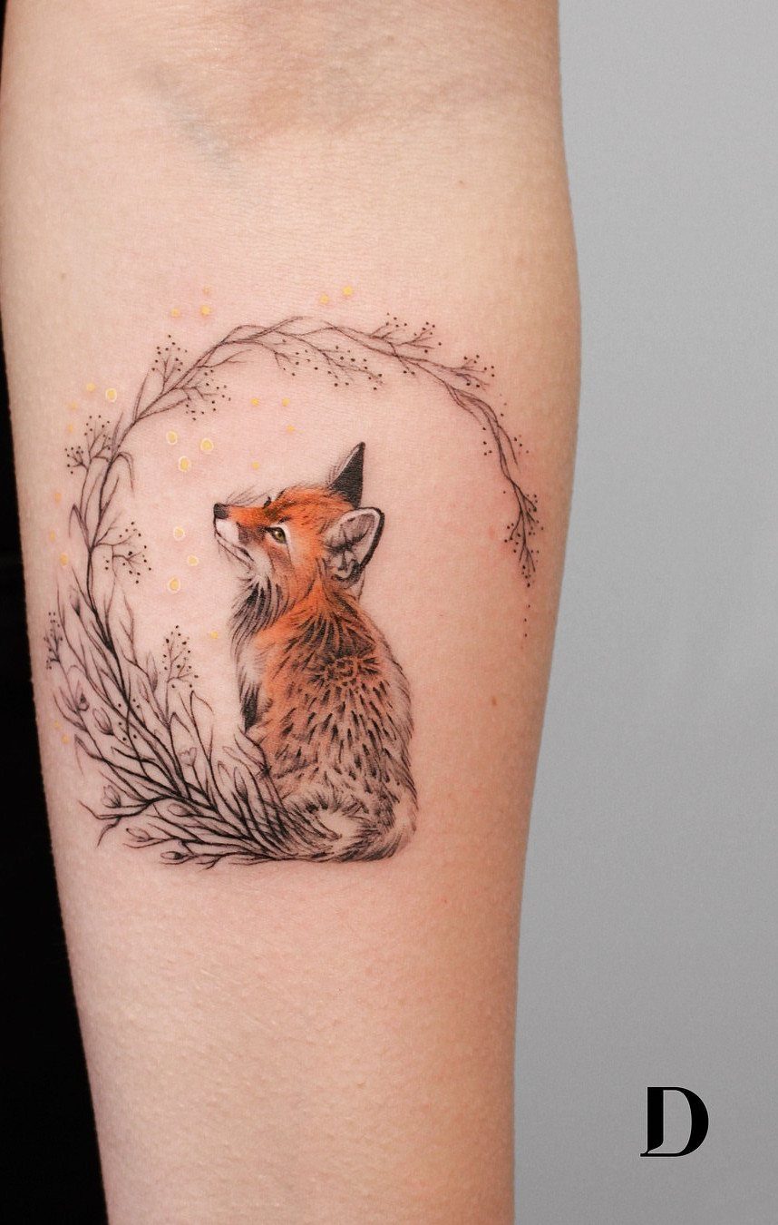 Fox tattoo on arm surrounded by a circular wreath of thin black branches.