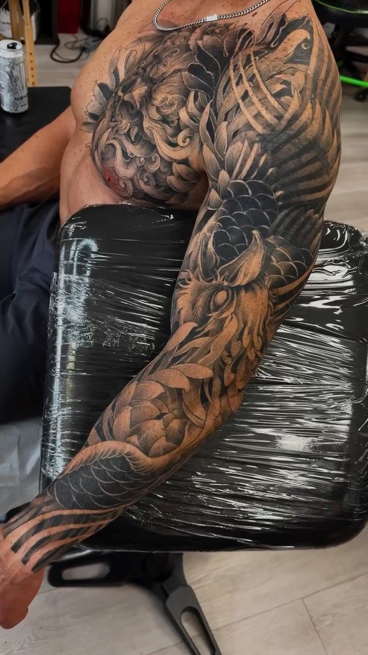 Detailed black and grey Japanese sleeve tattoo on a muscular arm and chest.