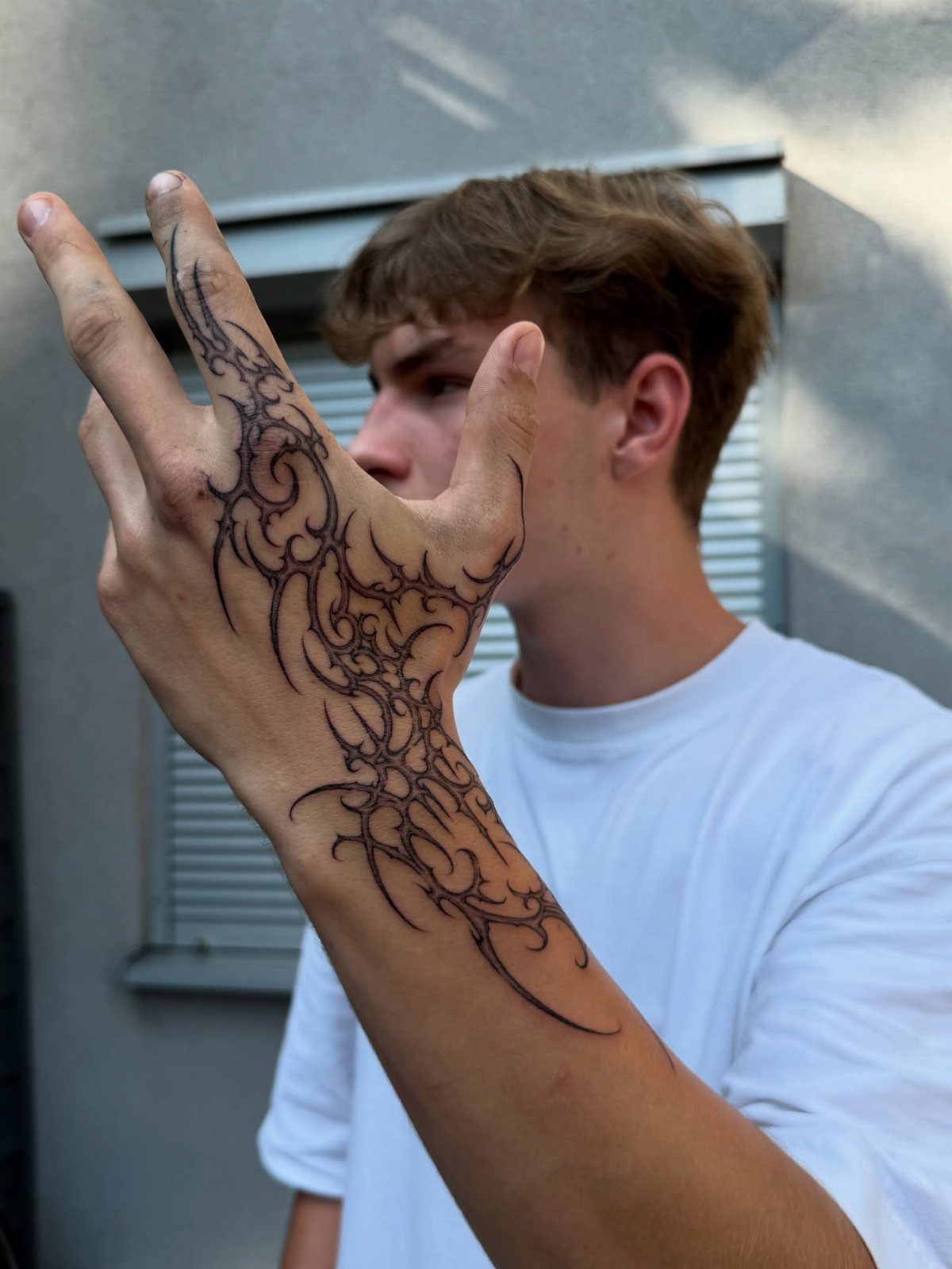 Man's hand and wrist with a black flowing tribal style tattoo