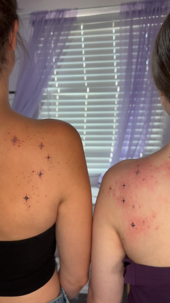 Two women showing star constellation tattoos on their upper backs and shoulders.