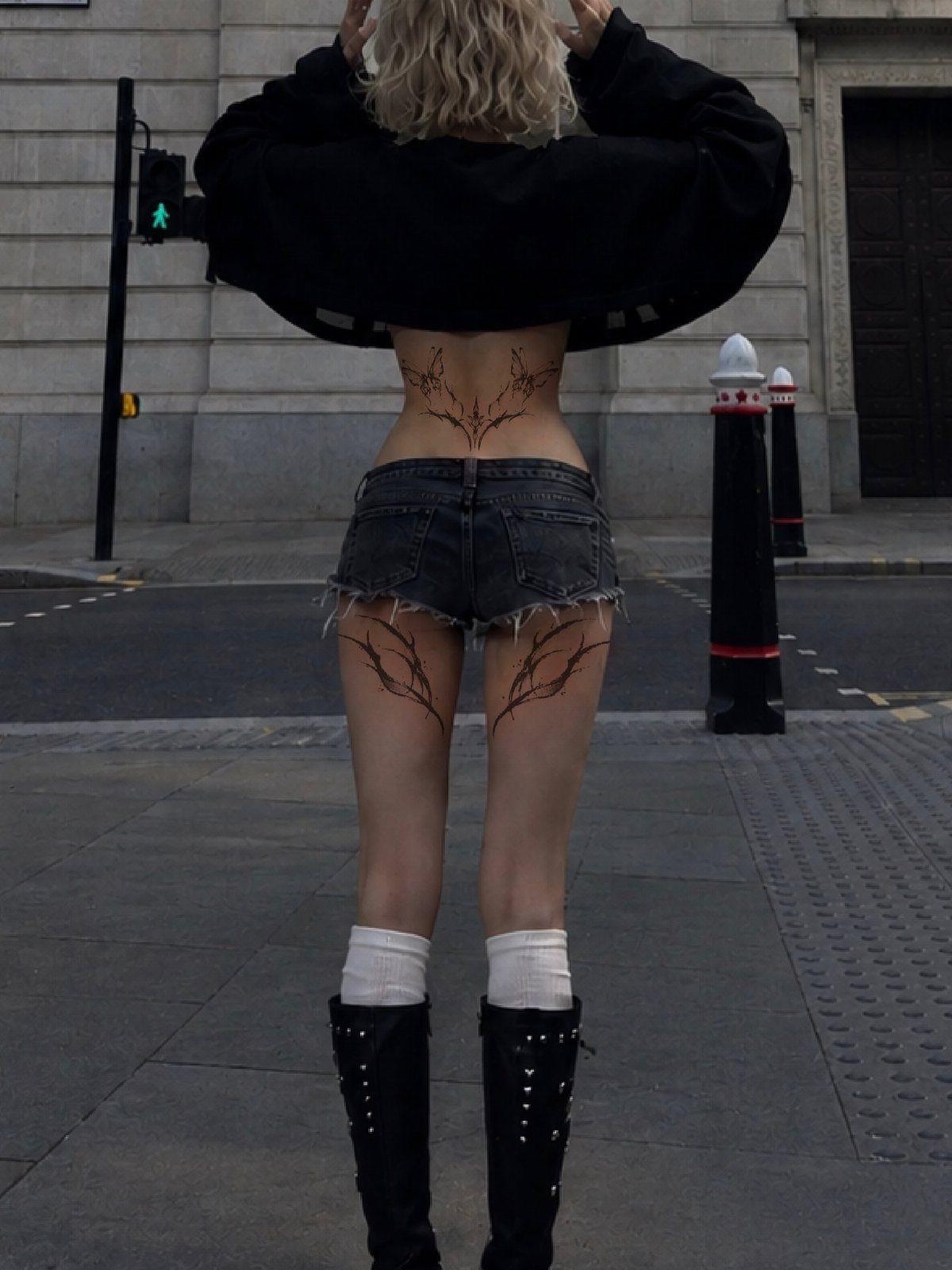 Woman with ornamental brown tattoos on her lower back and thighs in a city.