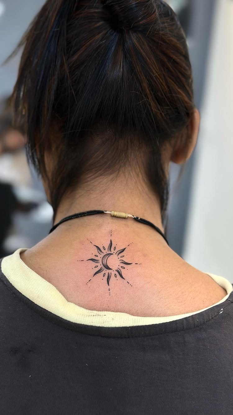 Sun and moon tattoo on the back of a person's neck.