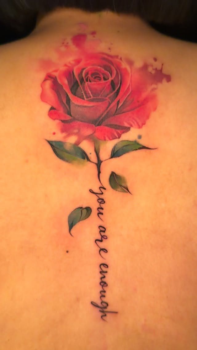 Red watercolor rose tattoo with a script quote on a person's back
