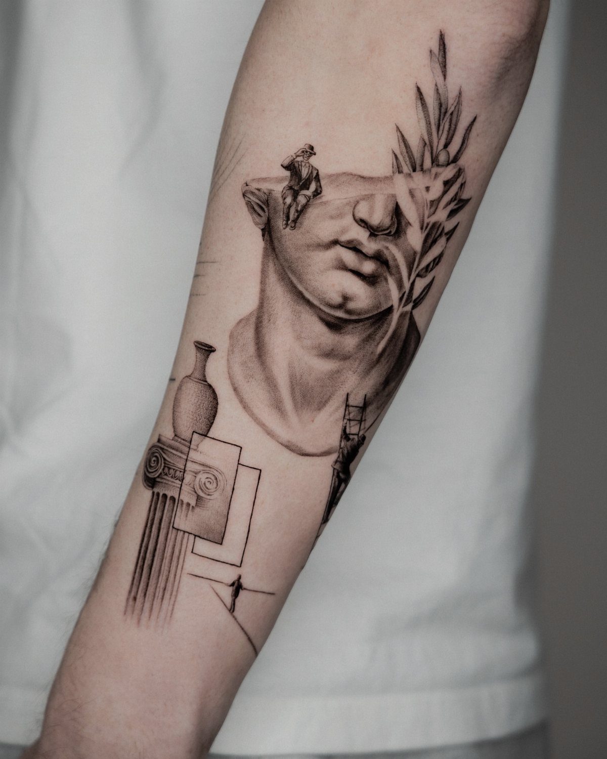 Classical Greek themed tattoo on a lower arm with a face and column.