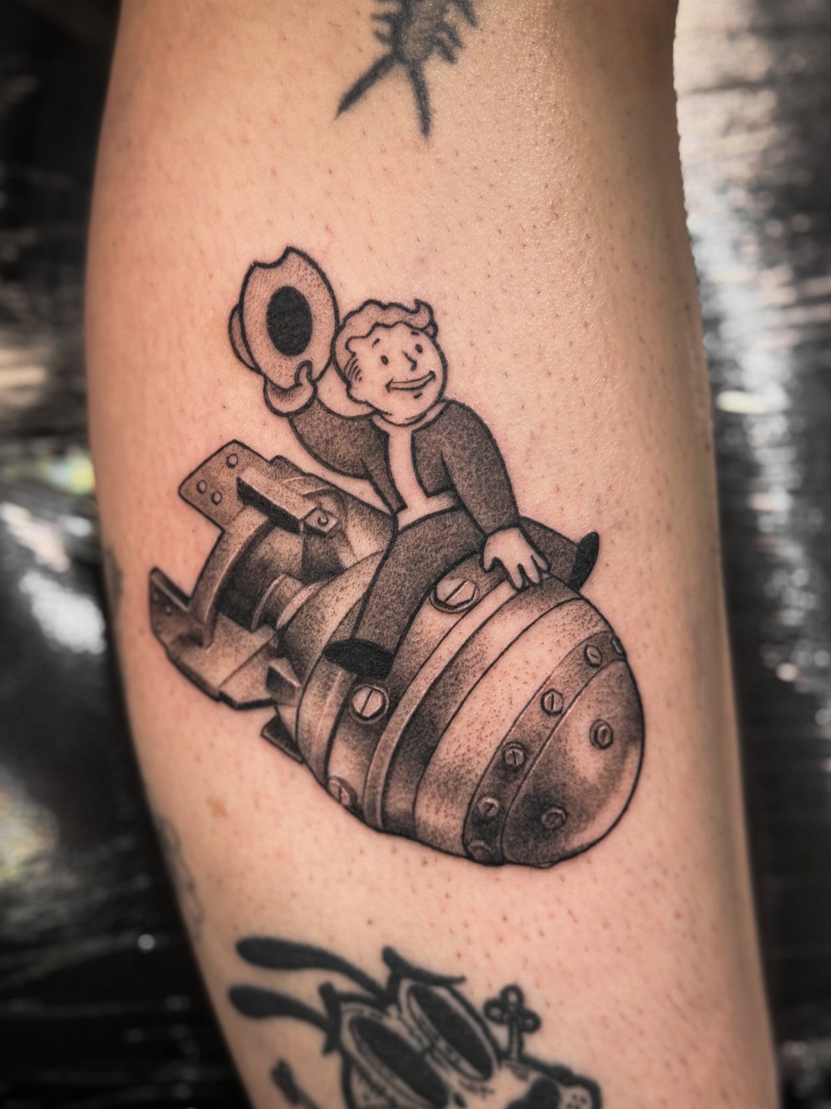 Vault Boy tattoo sitting on a nuclear bomb on a person's forearm