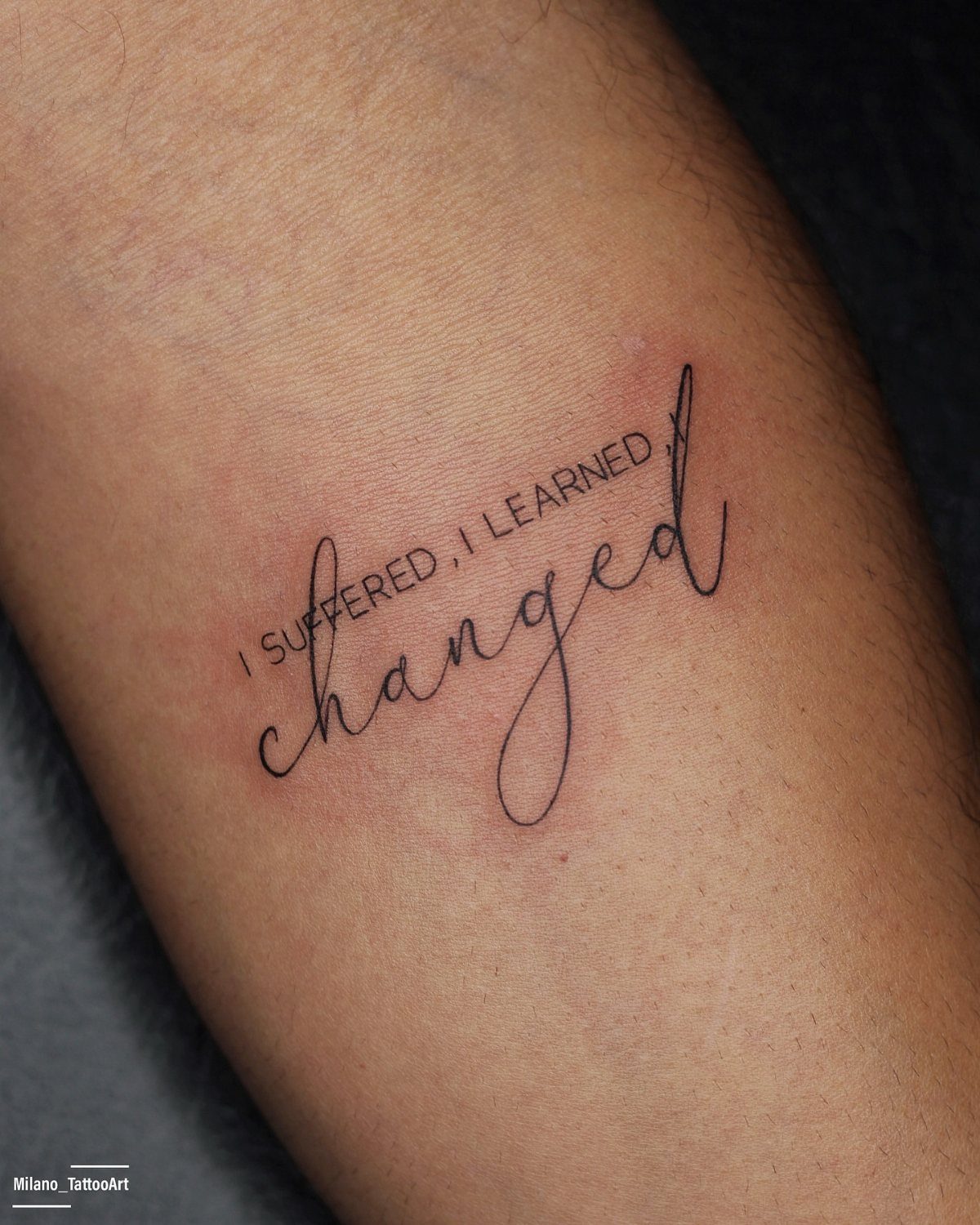 Quote tattoo on a forearm reading I suffered, I learned, changed in black ink.