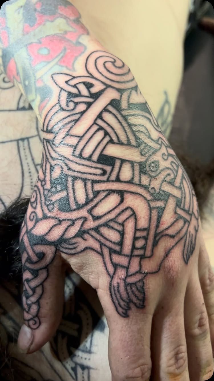 Celtic knotwork tattoo covering the back of a person's hand and wrist.