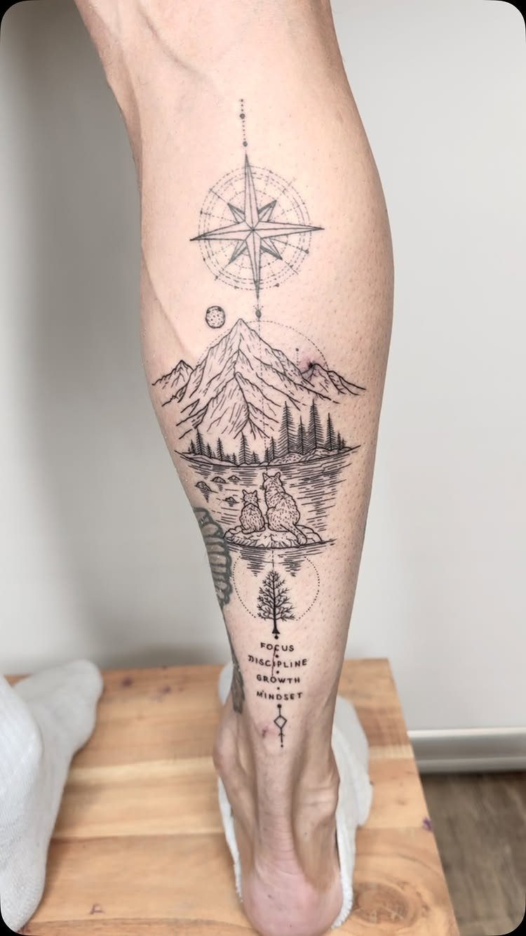 Mountain range tattoo with a compass and pine trees on a lower leg.