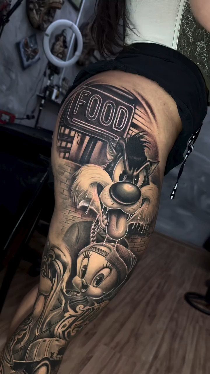 Black and grey leg tattoo featuring cartoon characters and a food sign.