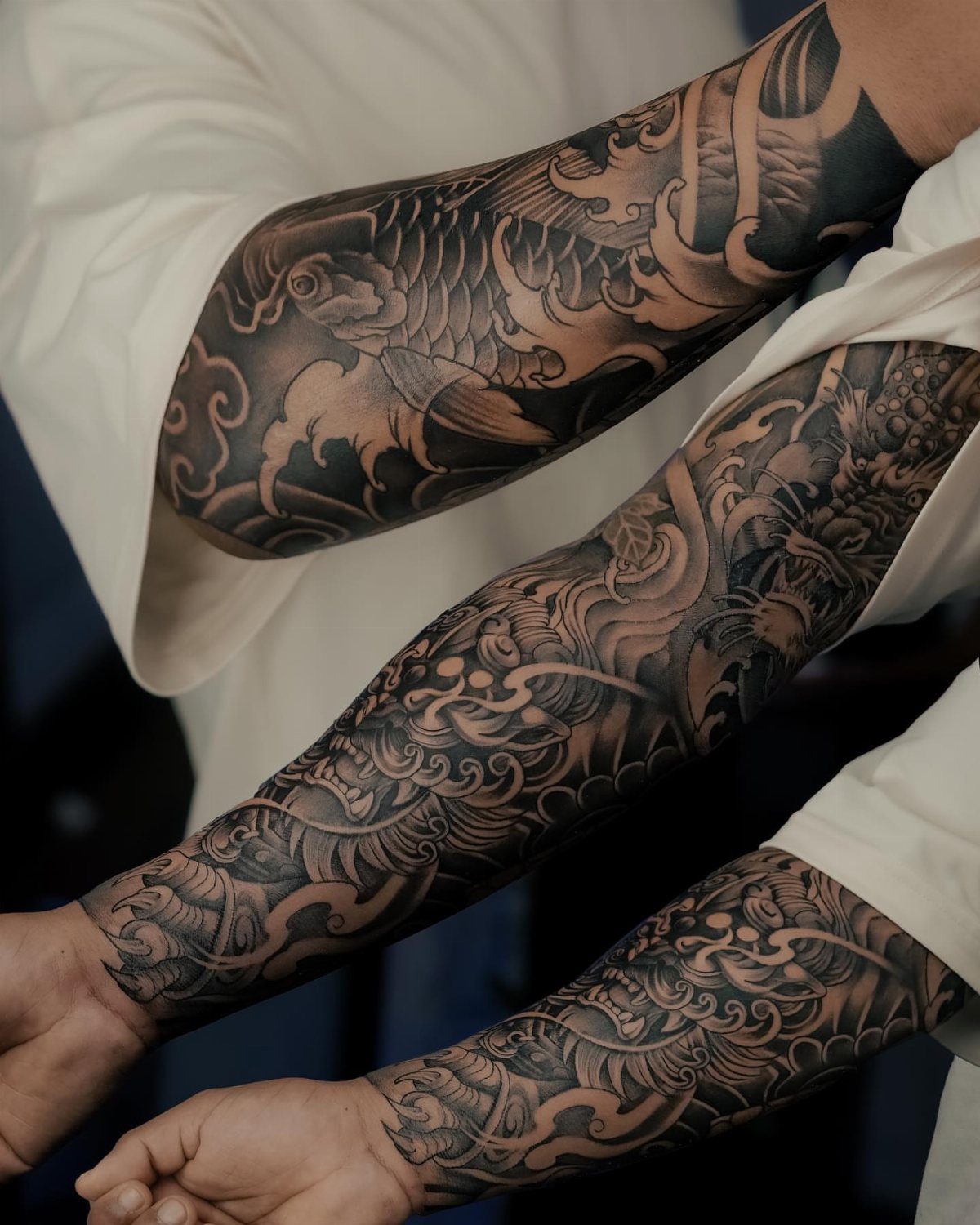 Detailed black and grey Japanese tattoo sleeves with koi fish and dragon motifs.