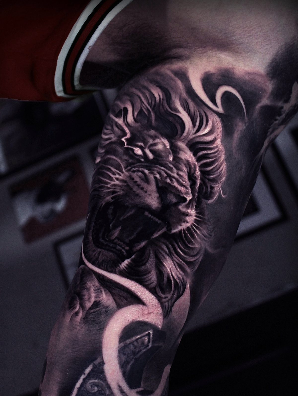 Roaring lion tattoo sleeve in black and grey ink on a man's arm.