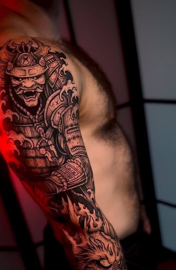 Detailed black and grey Japanese samurai tattoo sleeve on a man's muscular arm.