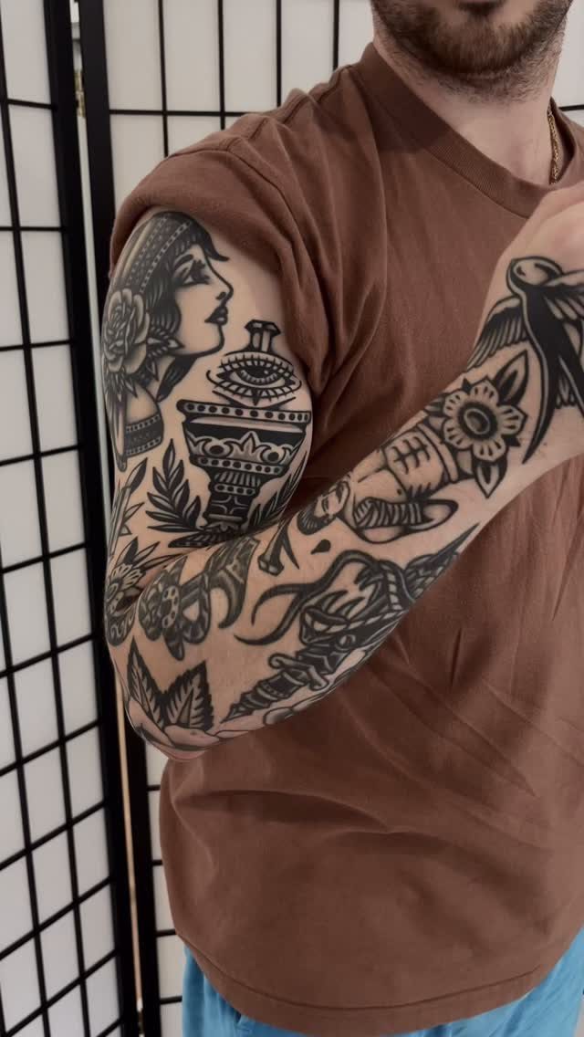 Man's arm with American traditional black ink tattoos including a woman and chalice.