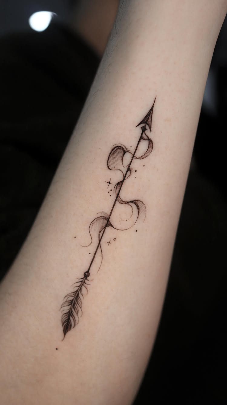 Black ink arrow tattoo with smoke swirls and stars on a person's forearm.