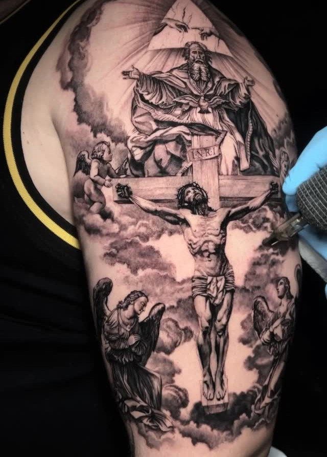 Religious tattoo on a man's arm depicting Jesus on the cross with angels.