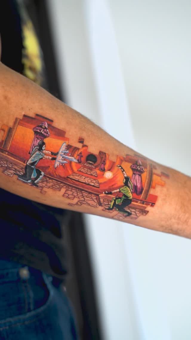 Colorful gaming scene tattoo on a forearm featuring characters in an orange environment.