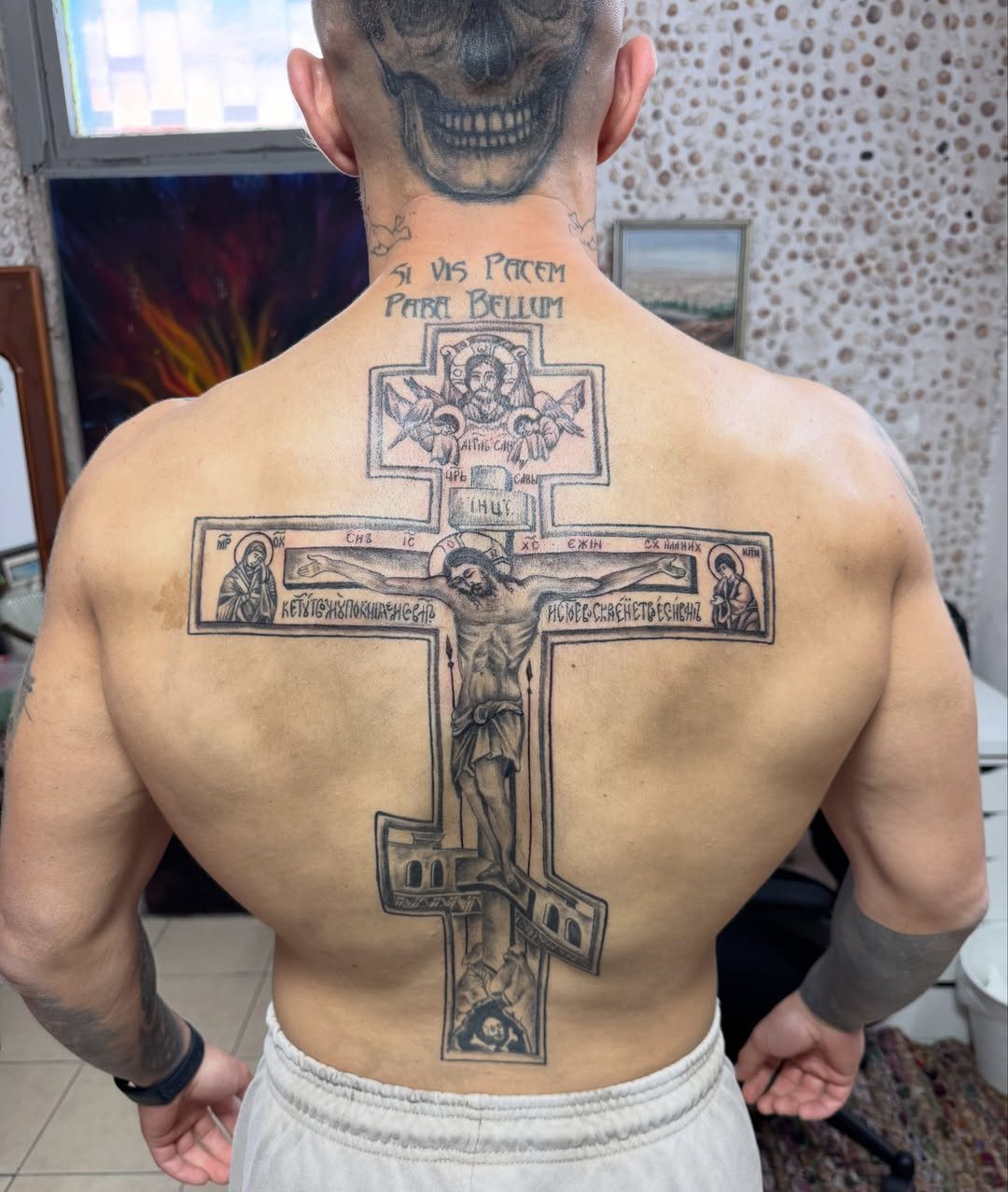 Large Orthodox cross tattoo on a man's back with a skull head tattoo.