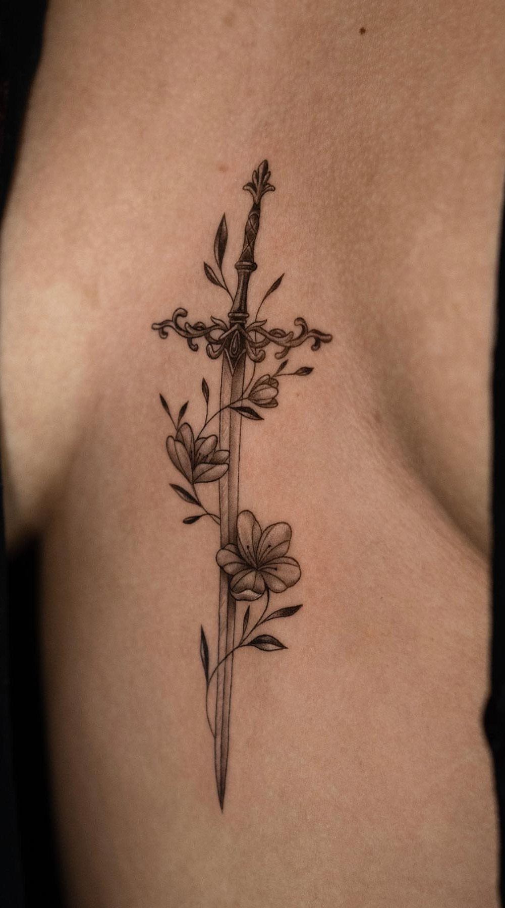 Sword and flower tattoo located on the center of a person's chest.