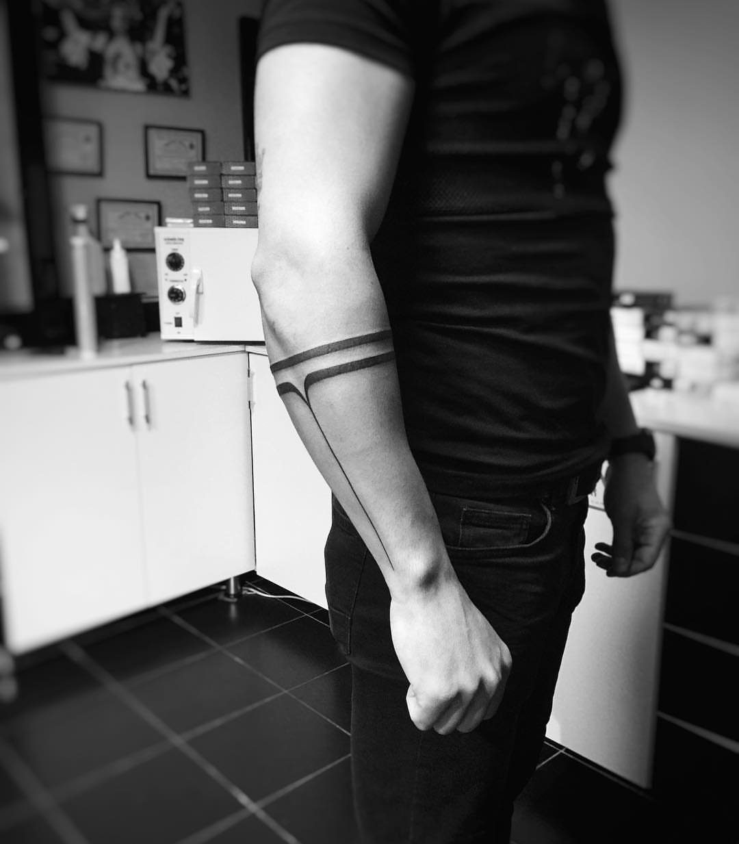 Man's forearm with a minimalist line tattoo consisting of bands and a vertical line.