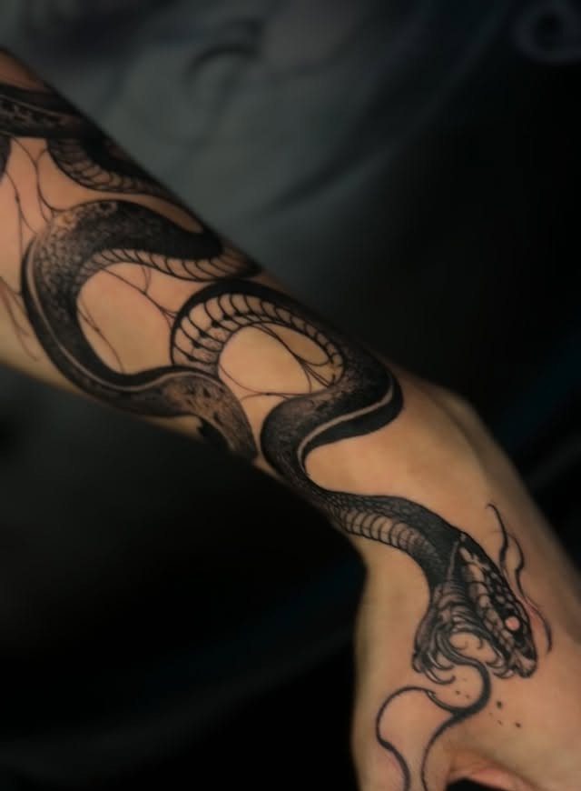 Snake tattoo winding around a person's forearm and extending toward the hand.