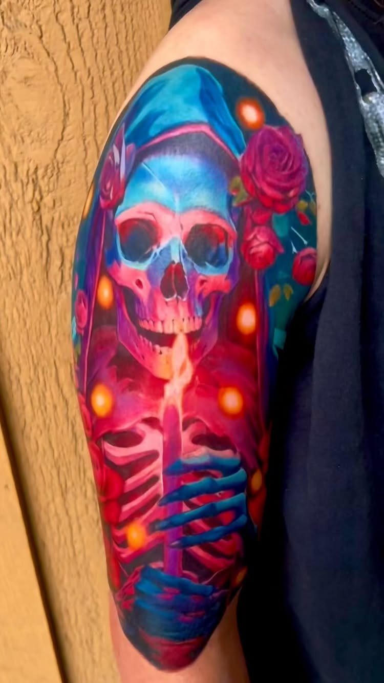 Colorful tattoo of a skull and pink roses on a man's upper arm.