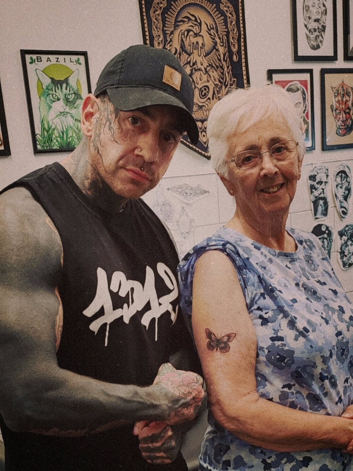 Older woman with white hair showing a small butterfly tattoo on her upper arm.