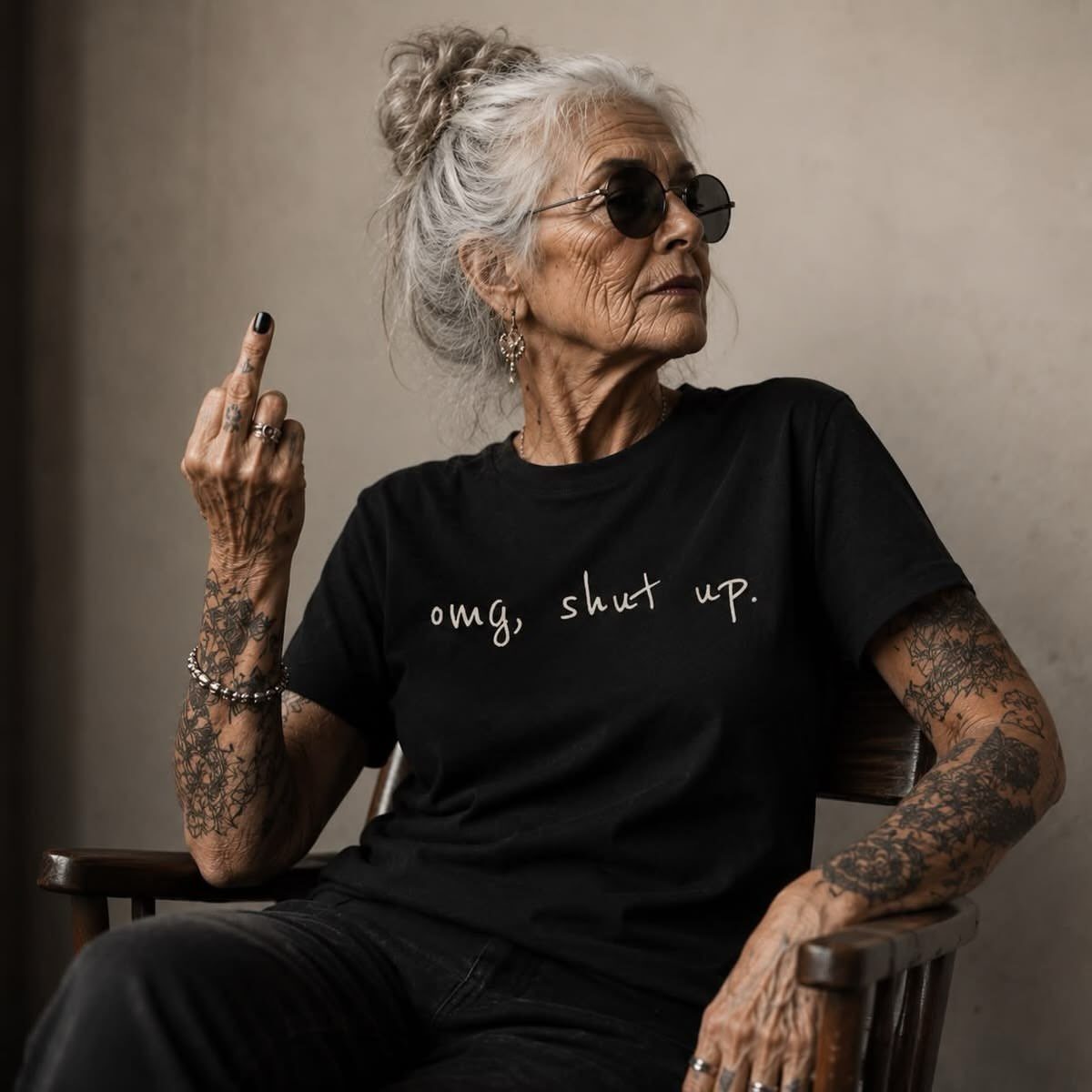 Older woman with grey hair and sunglasses showing tattoos on her arms and hands.
