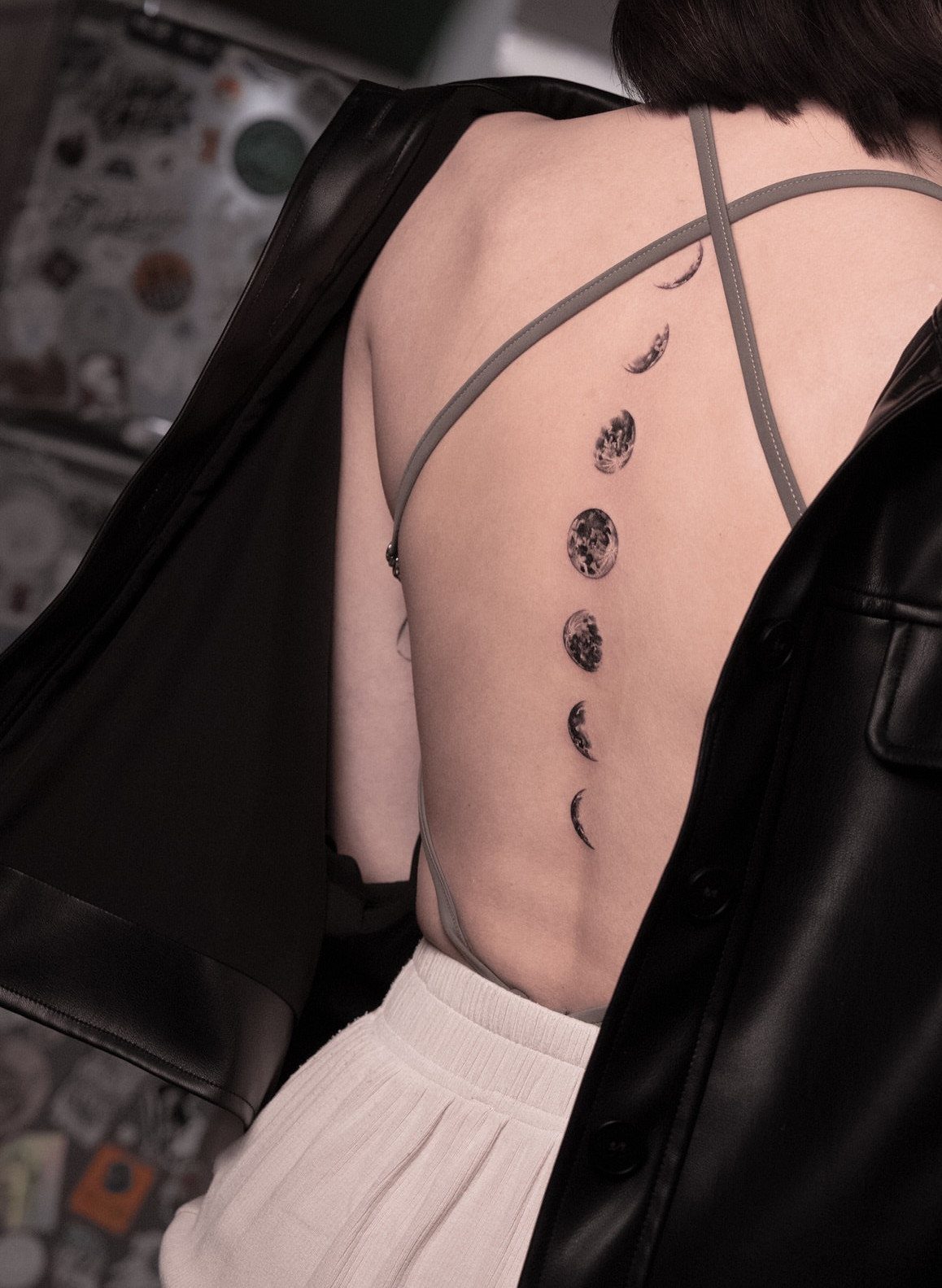 Moon phase tattoos in a vertical line on a person's back.