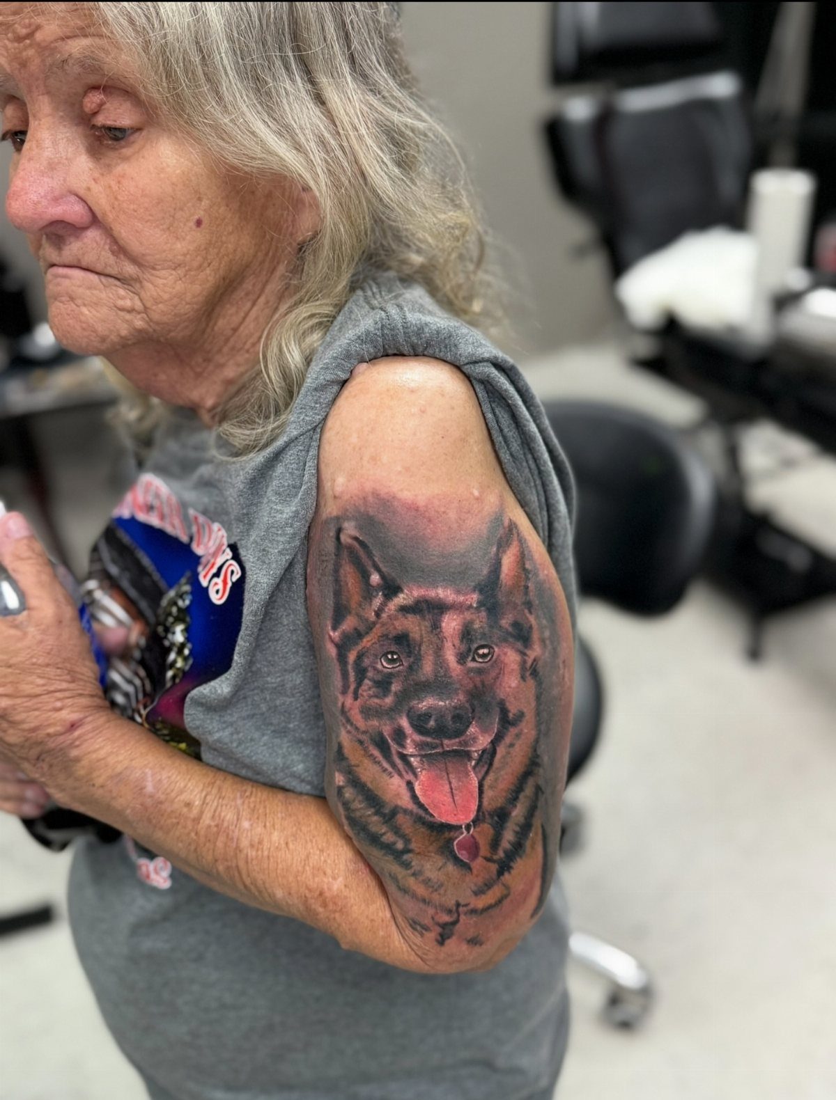 Older woman with a realistic German Shepherd dog tattoo on her upper arm.