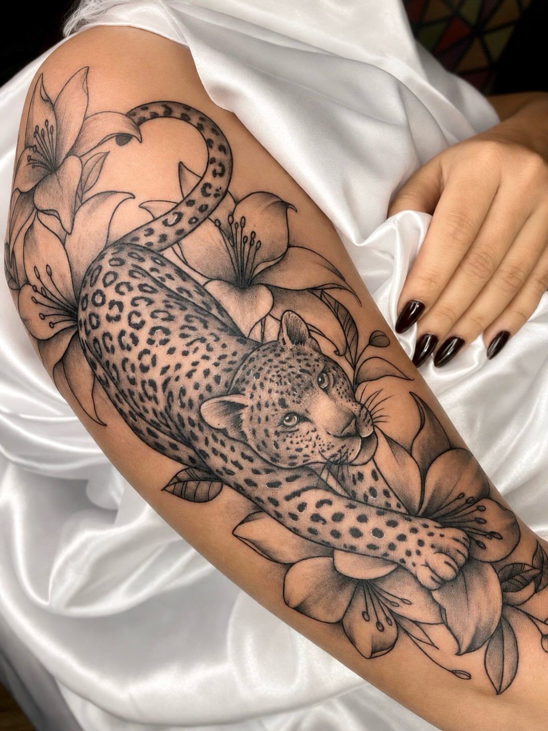 Leopard half sleeve tattoo with lilies on a woman's arm.
