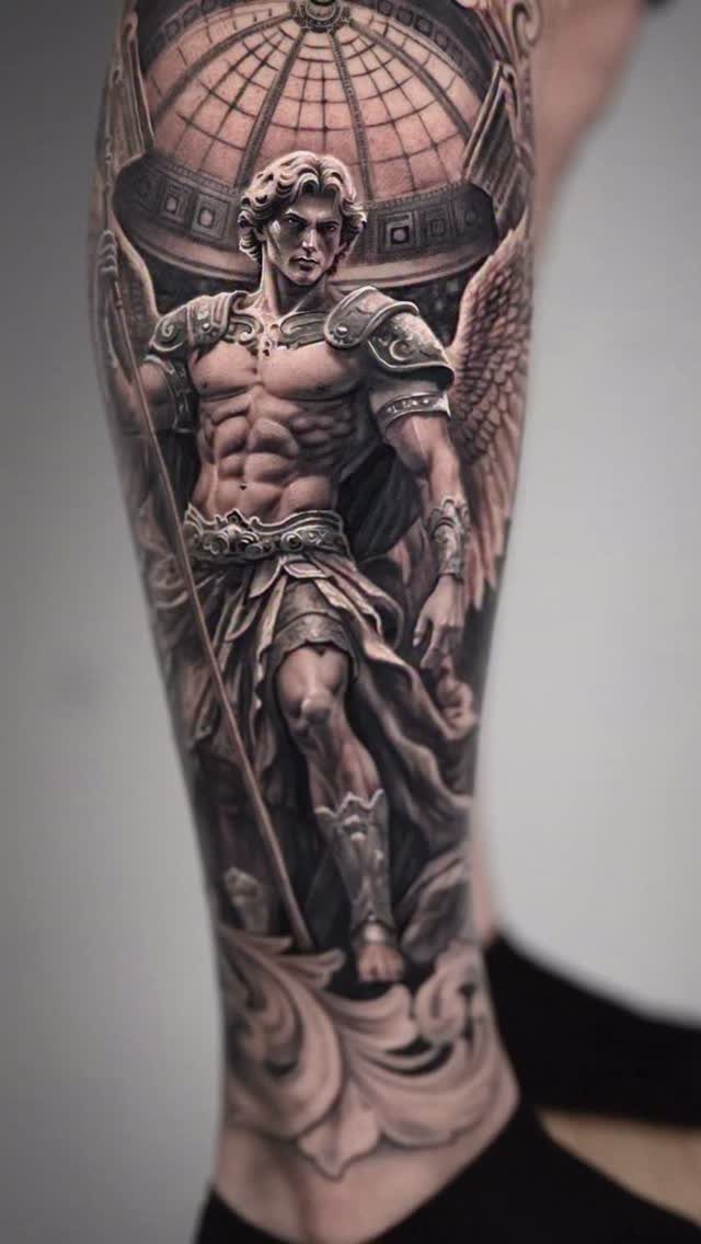 Muscular male angel in Roman armor tattooed in black and grey on a man's arm