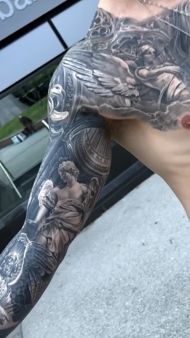 Detailed black and grey tattoo sleeve on a man's arm featuring classical angels.