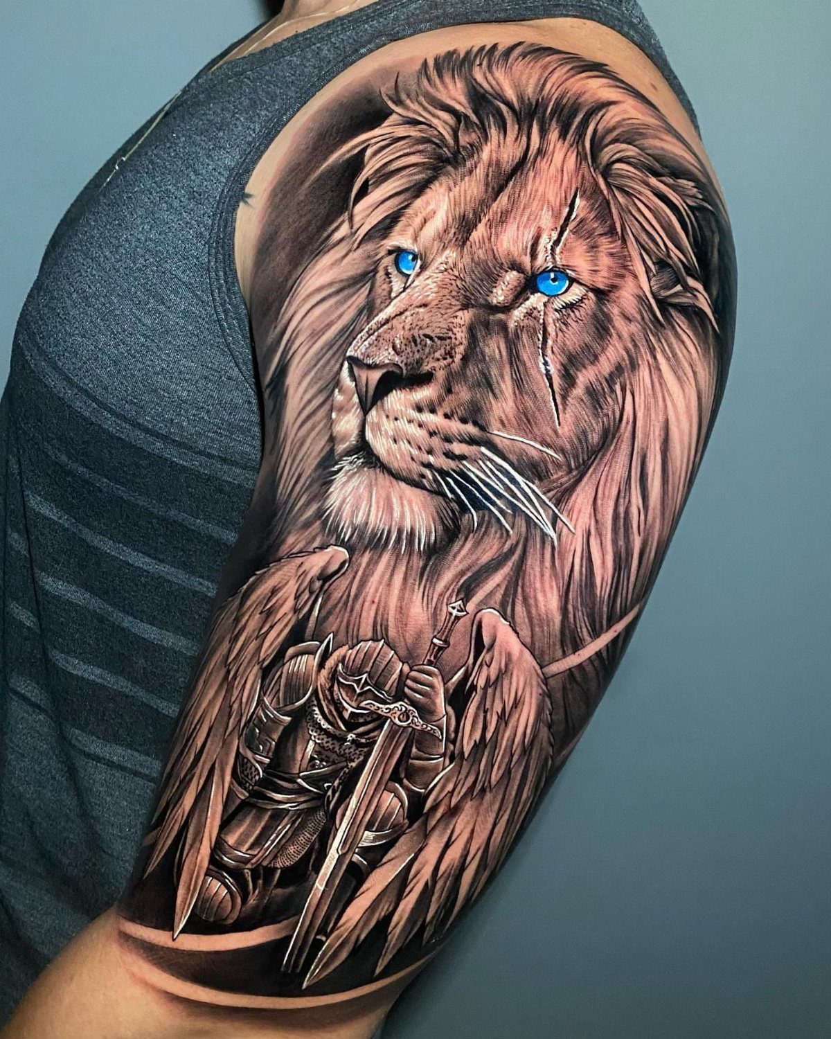 Lion tattoo with blue eyes and a winged knight on a man's arm