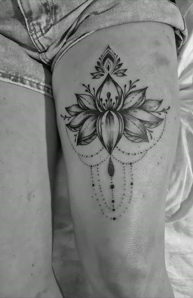 Lotus flower tattoo with ornamental dotwork on a woman's upper thigh.