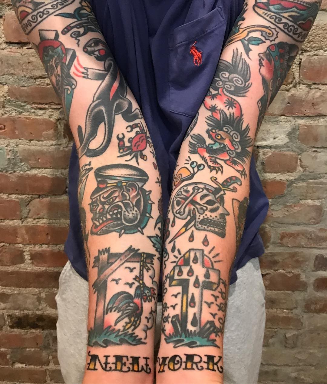 Tattooed arms featuring American traditional sleeve designs with a panther, skull, and cross.