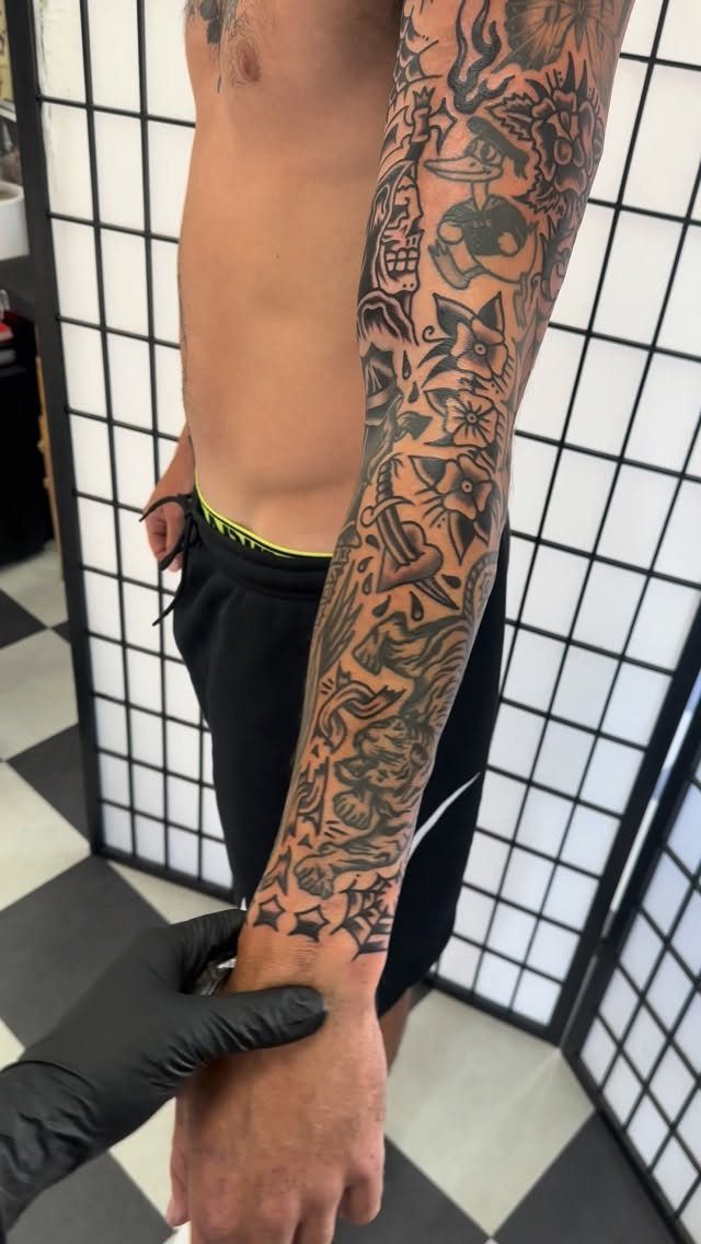 Full sleeve of traditional black and grey tattoos on a person's arm