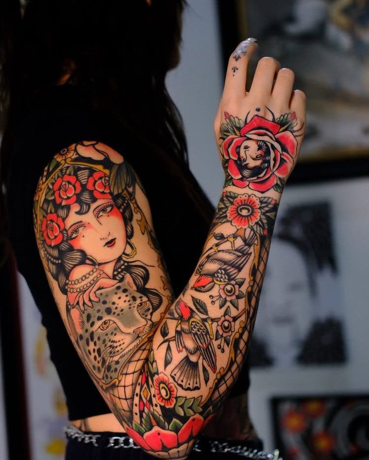 Traditional tattoo sleeve on an arm featuring a woman, leopard, and red roses.