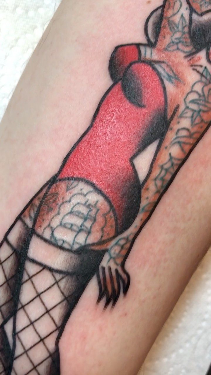 Pin-up woman tattoo with red bodice and fishnet stockings on skin