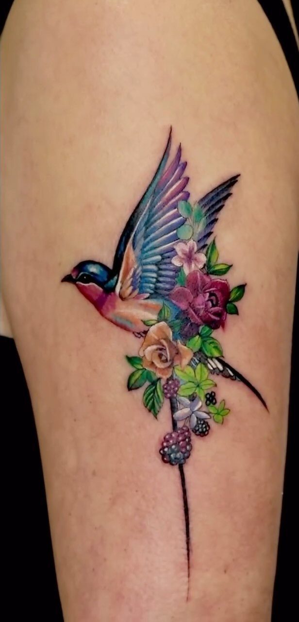 Swallow bird tattoo with colorful flowers on a person's arm or leg.