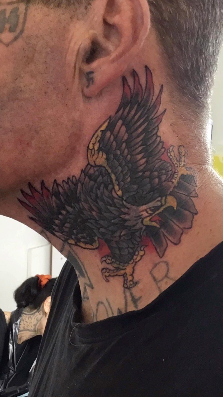 Traditional black and red eagle tattoo on a man's neck.
