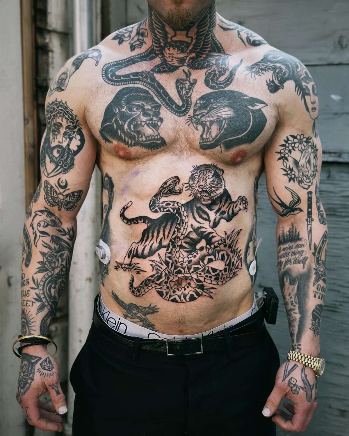 Man with traditional tattoos including a tiger and snake on his stomach.
