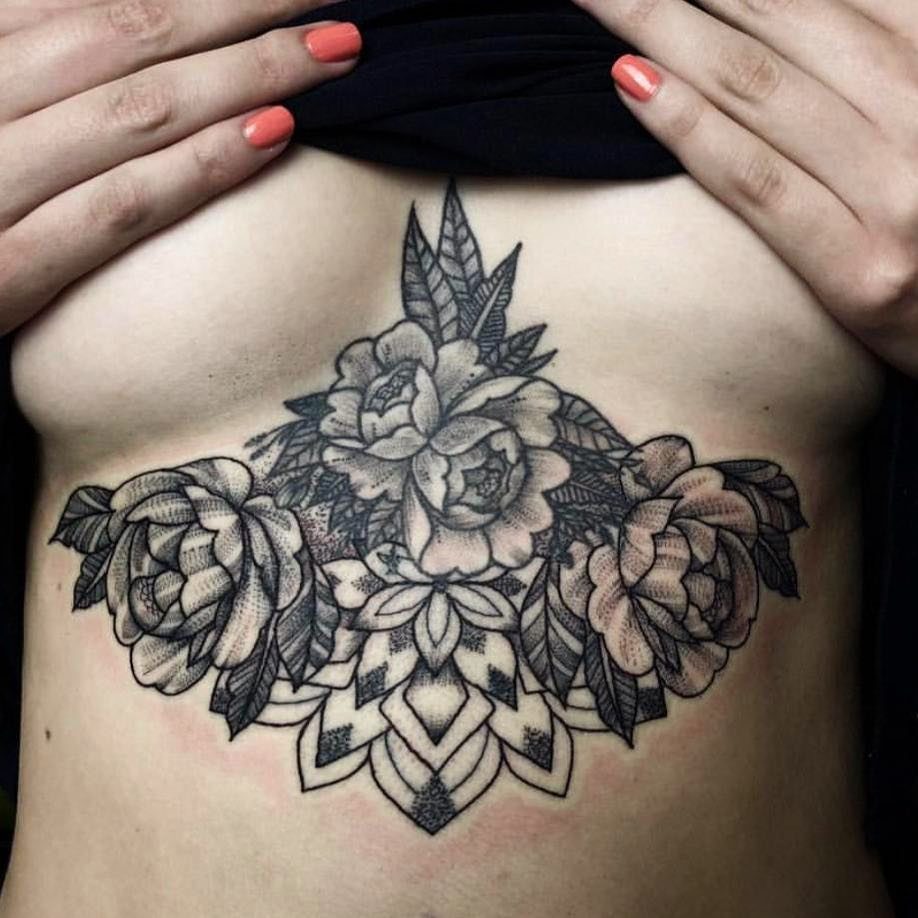Floral and geometric tattoo on a woman's chest and underboob area.