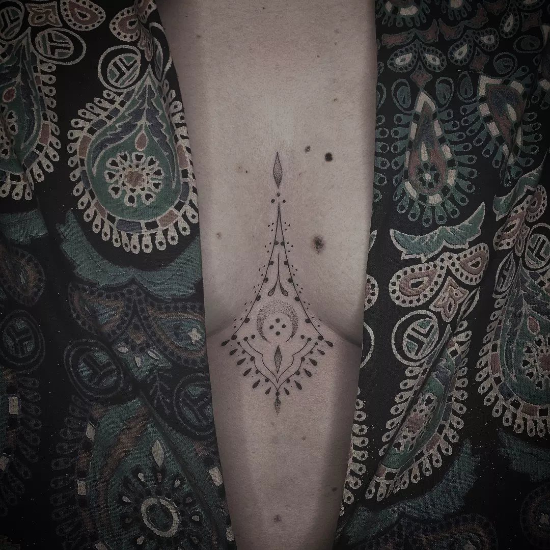 Symmetrical geometric sternum tattoo with dots and lines on a person's chest.