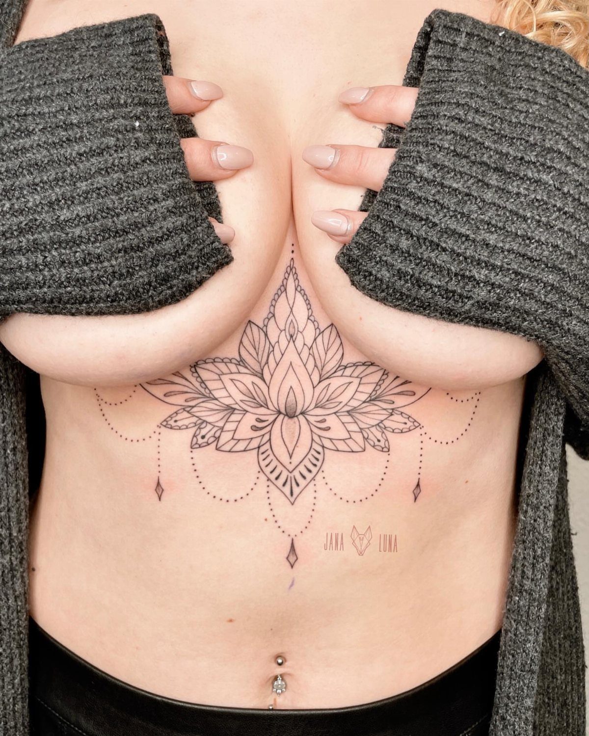 Woman with a symmetrical lotus flower and jewelry tattoo under her breasts.