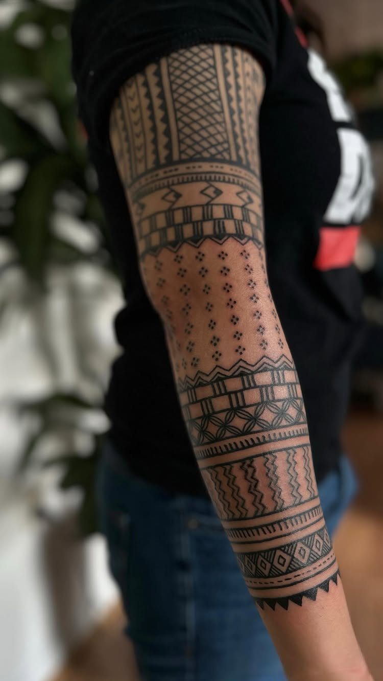 Upper arm tattoo with bold black geometric patterns and tribal-style line work.