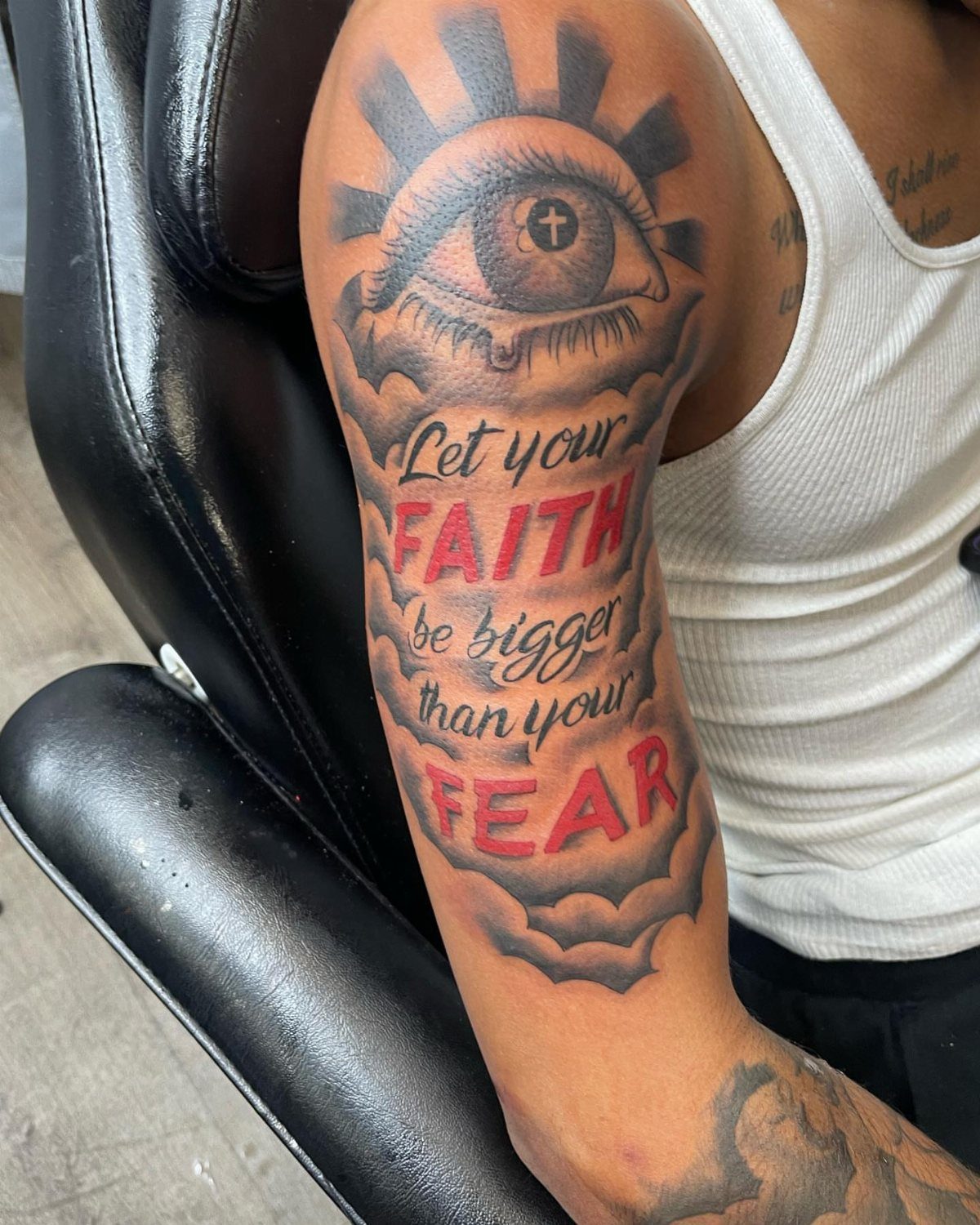 Upper arm tattoo featuring an eye and the quote Let your faith be bigger than your fear